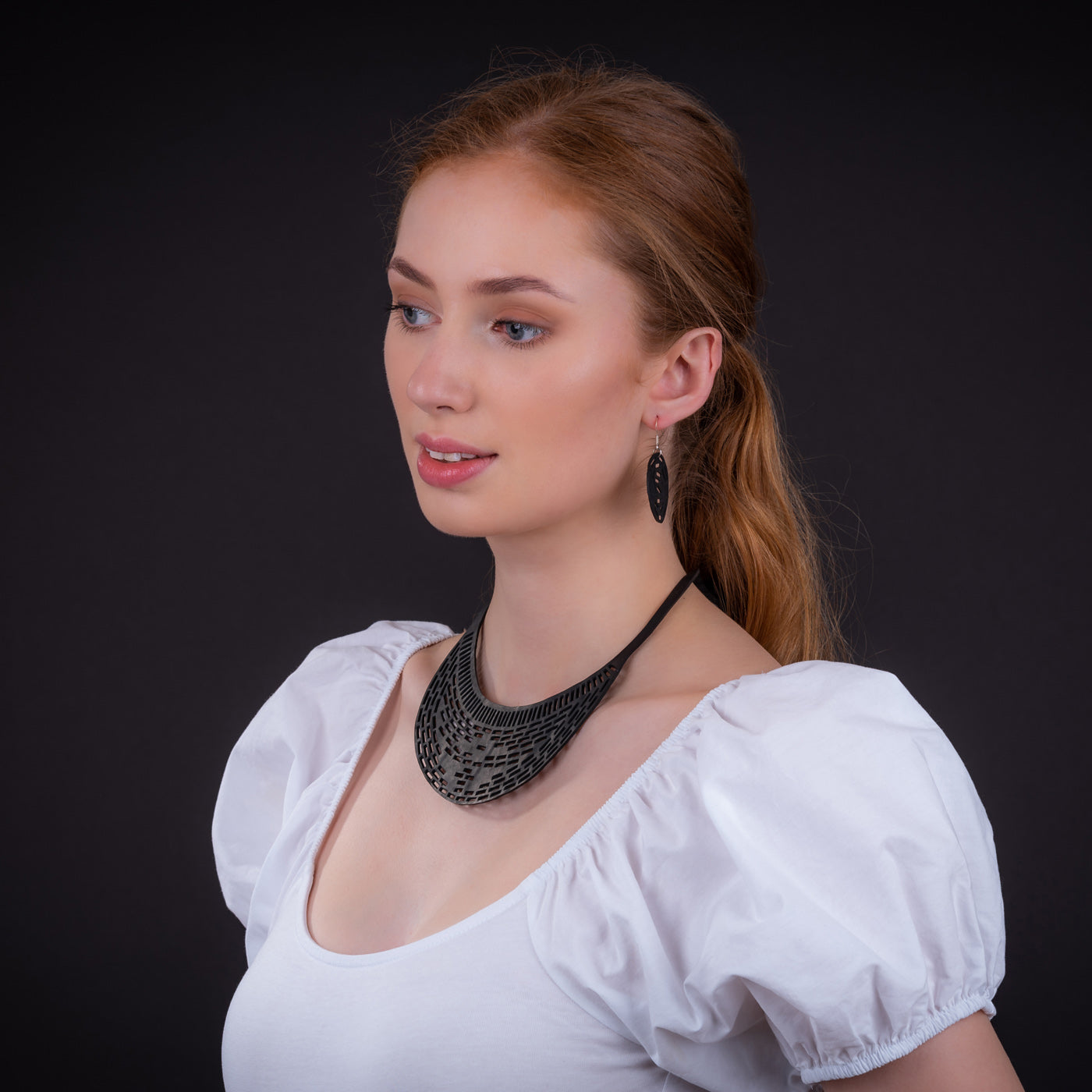 Paguro Upcycle recycled rubber earrings worn by model with black statement necklace and white puff sleeve top
