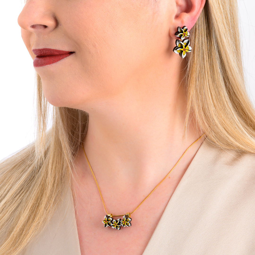 Paguro Upcycle reclaimed wood necklace featuring small yellow and white flower designs on a gold chain