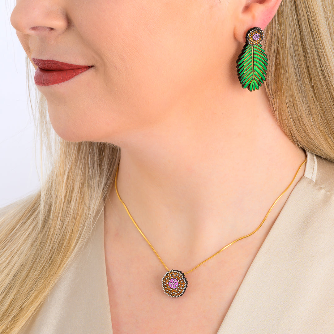 Paguro Upcycle reclaimed wood earrings shaped like green leaves worn on a woman with matching necklace