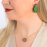 Paguro Upcycle reclaimed wood earrings shaped like green leaves worn on a woman with matching necklace