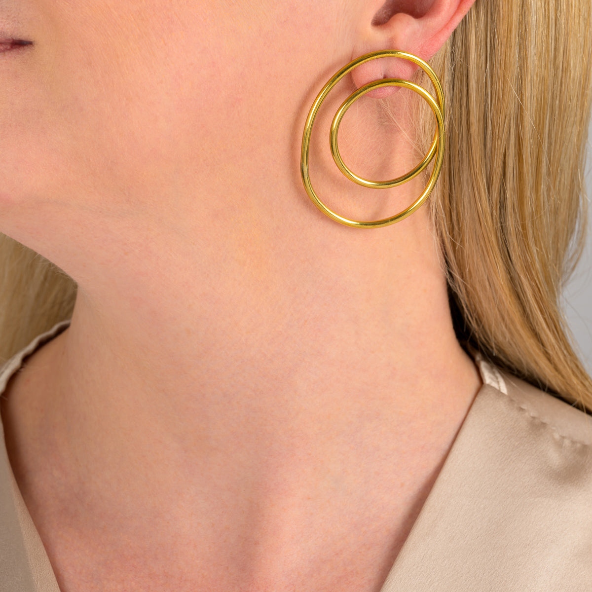 Paguro Upcycle recycled brass earrings in a double hoop design worn on a woman's ear
