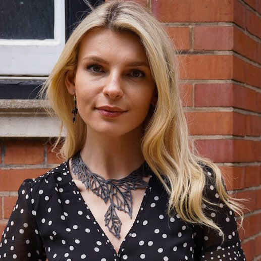 Woman wearing a recycled rubber leaf necklace by Paguro Upcycle in black with intricate leaf design