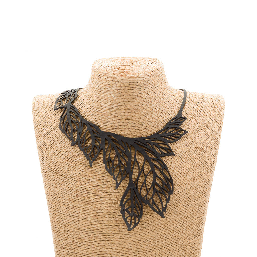 Paguro Upcycle recycled rubber leaf necklace with black layered leaf design on woven display bust