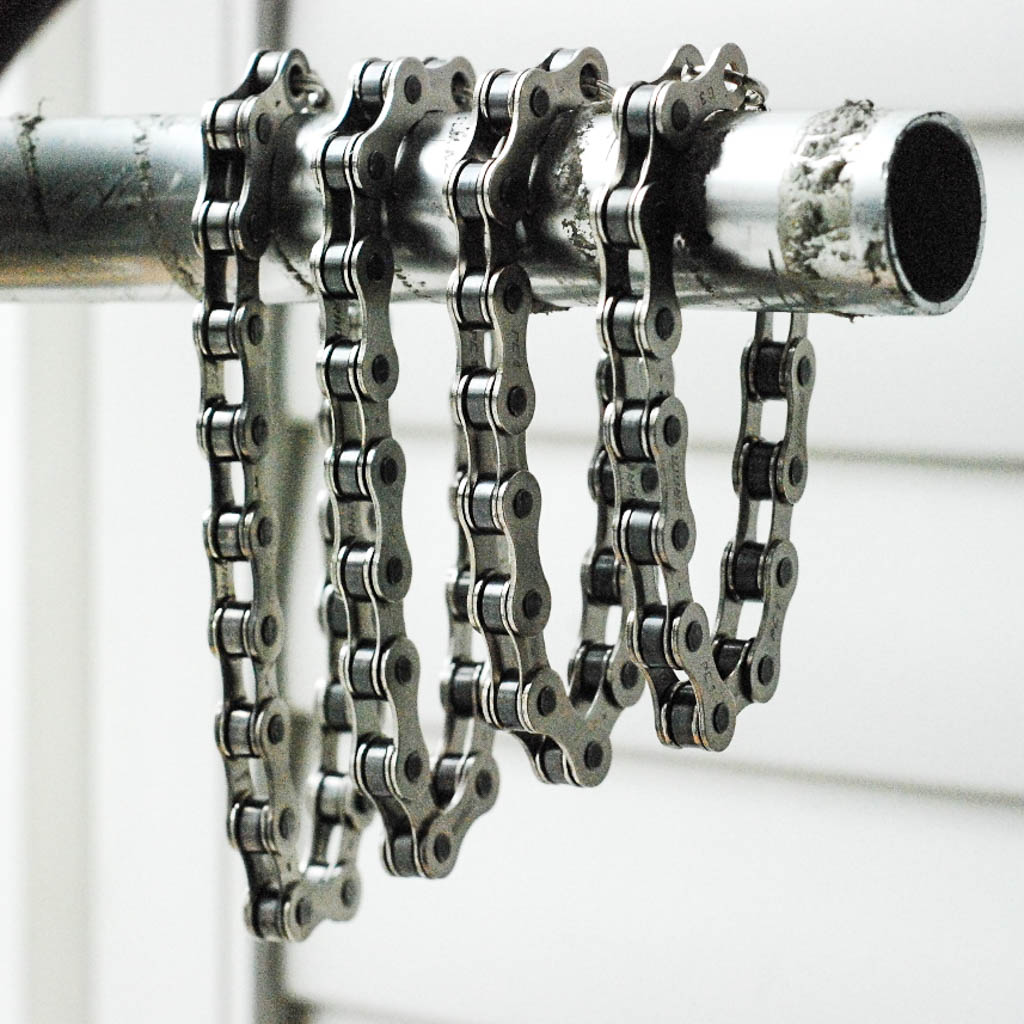 Paguro Upcycle recycled bike chain bracelet hanging on metal pipe showcasing upcycled durable design