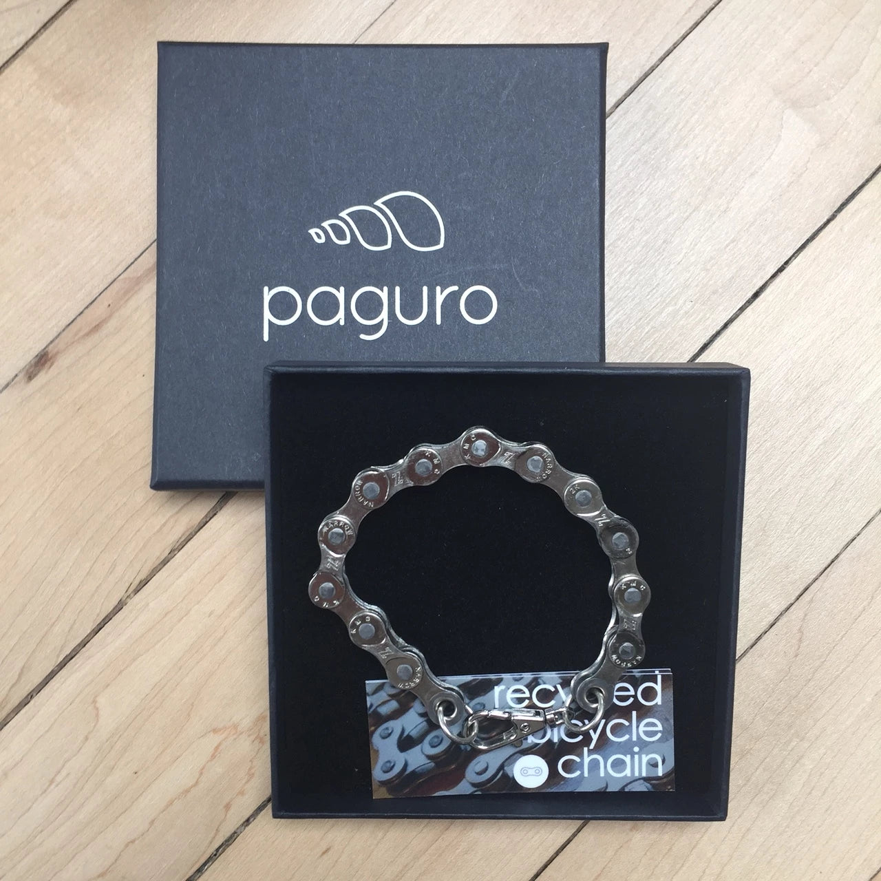 Paguro Upcycle recycled bike chain bracelet displayed in a black gift box on wooden floor