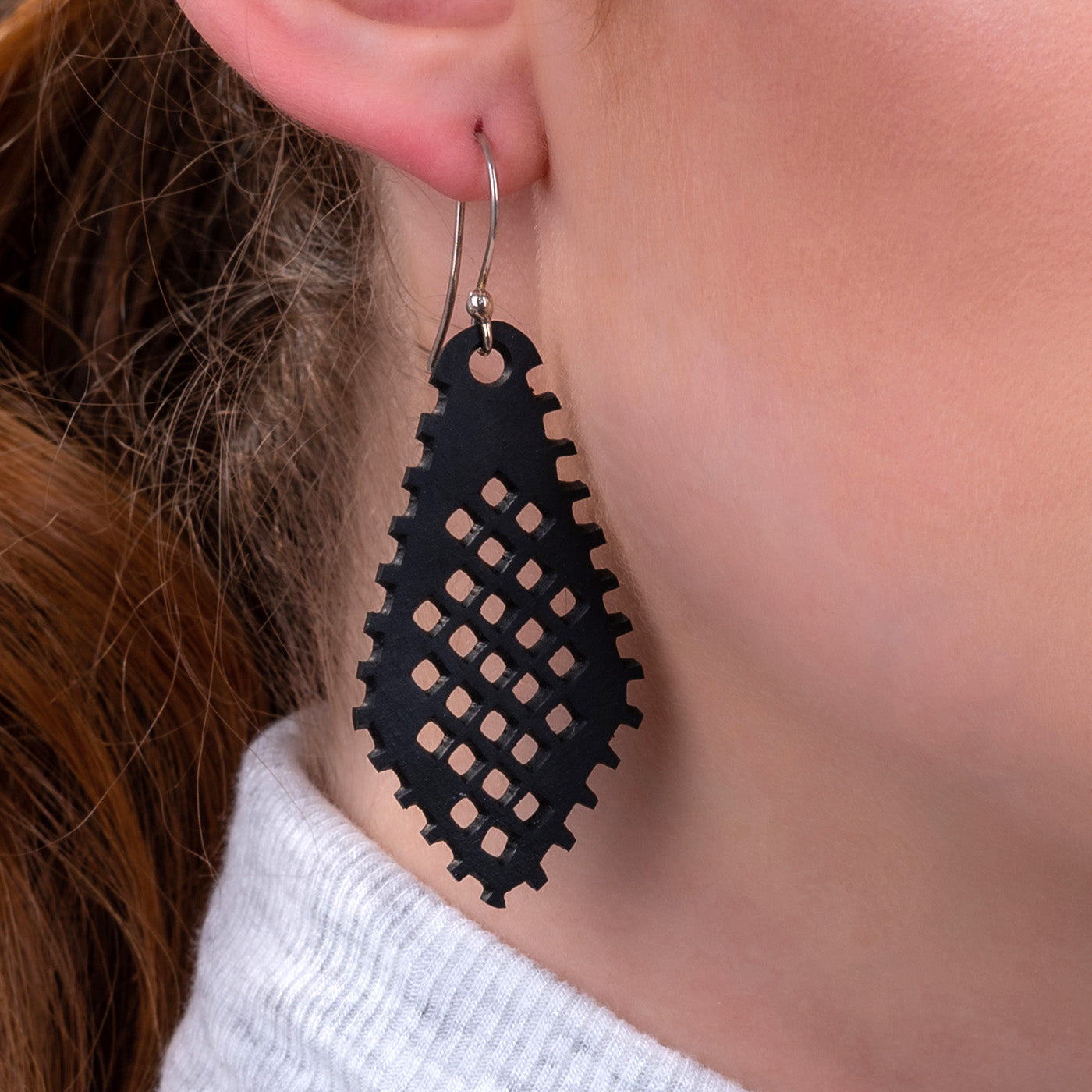 Paguro Upcycle black recycled rubber earrings with geometric cutout design worn on ear