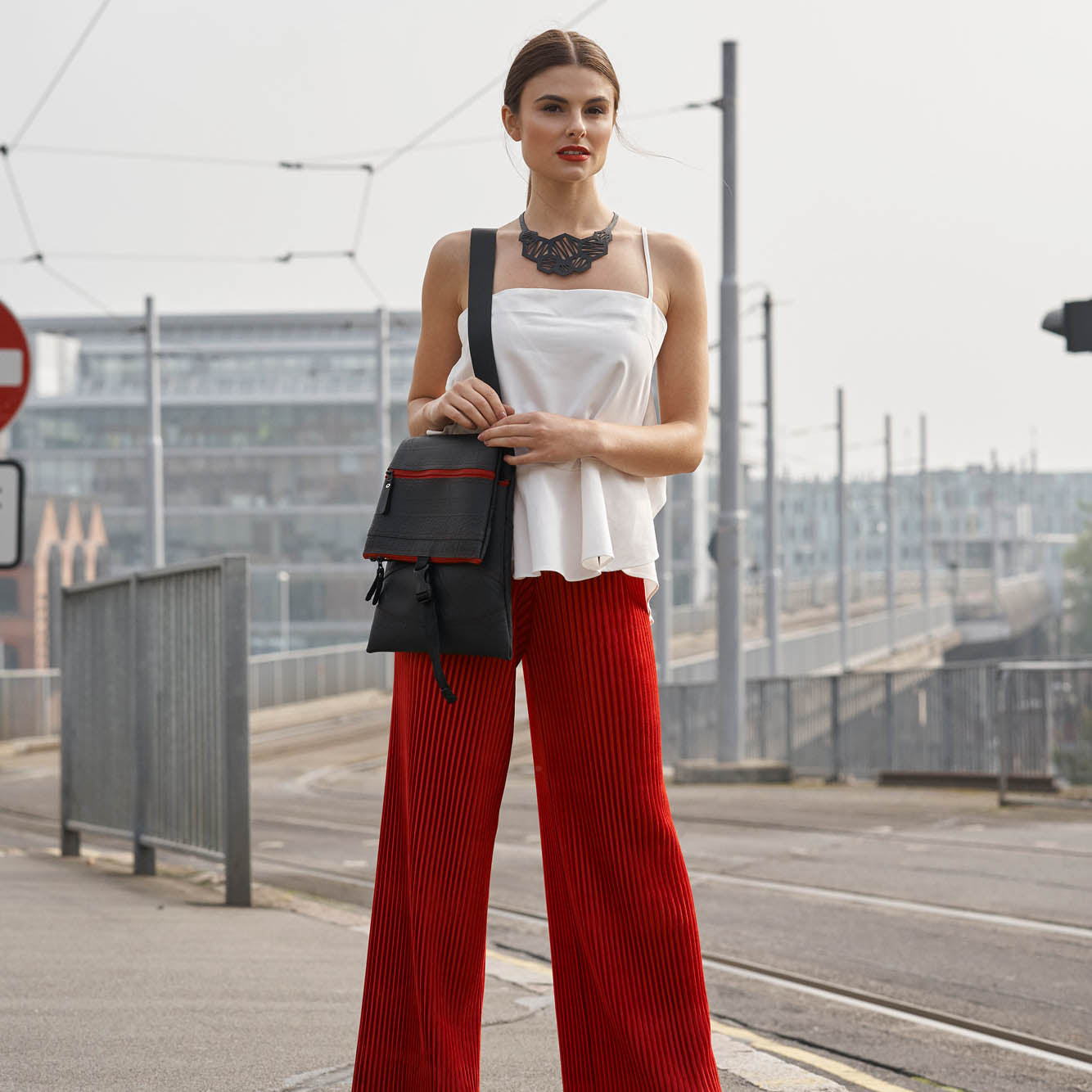 Paguro Upcycle recycled rubber necklace worn by model with white top red pants and black crossbody bag