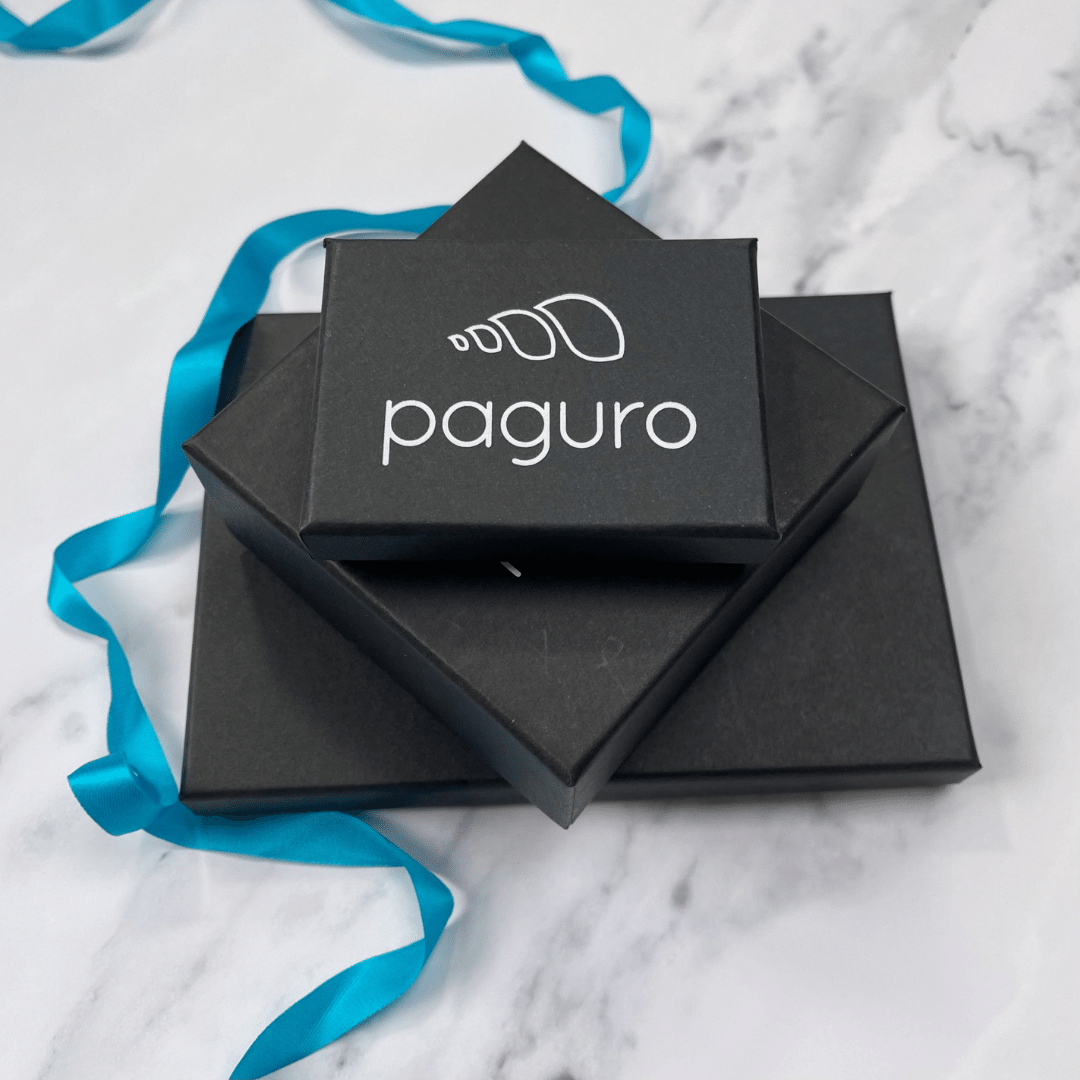 Paguro Upcycle black jewelry boxes stacked with blue ribbon on marble surface for upcycled feather necklace