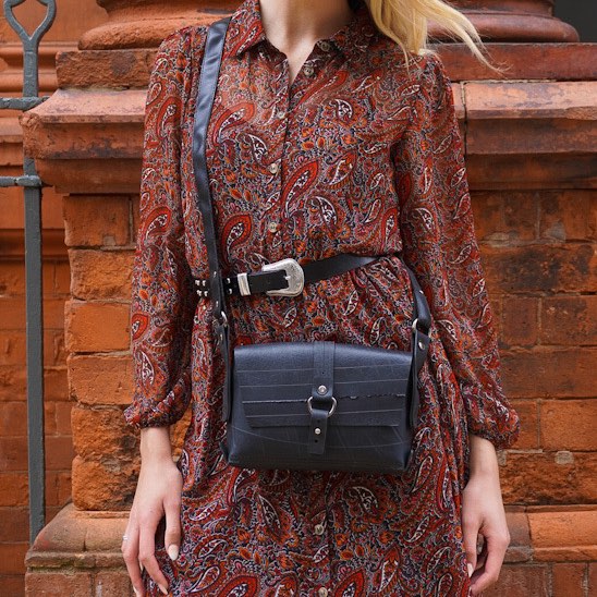 Paguro Upcycle recycle rubber vegan handbag displayed with an elegant dress against a brick wall