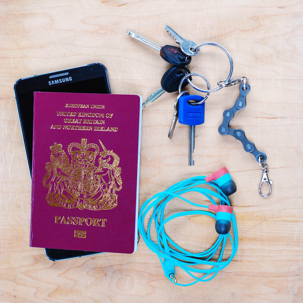 Paguro Upcycle recycled bike chain keyring attached to keys alongside passport phone and earbuds