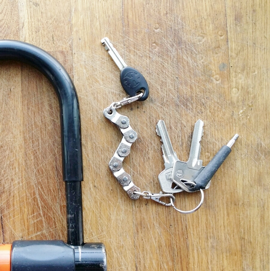 Paguro Upcycle recycled bike chain keyring holding multiple keys on wooden surface next to bike lock