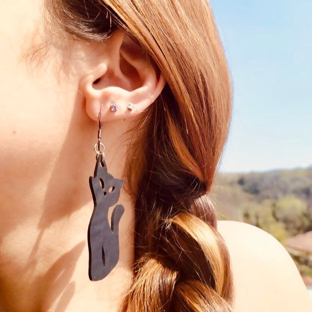 Paguro Upcycle recycled rubber cat earrings worn on a woman's ear with braided hair