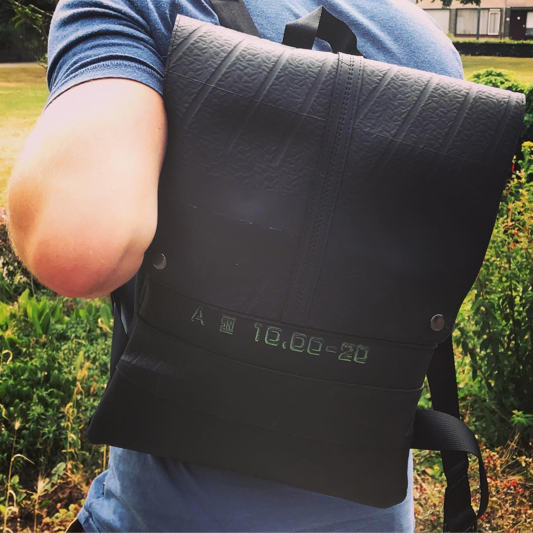 Paguro Upcycle vegan inner tube backpack in black worn by person outdoors featuring durable recycled material
