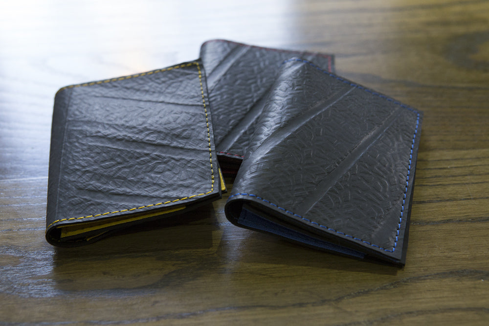 Paguro Upcycle vegan slim card holder wallets in black with colored stitching on wooden surface