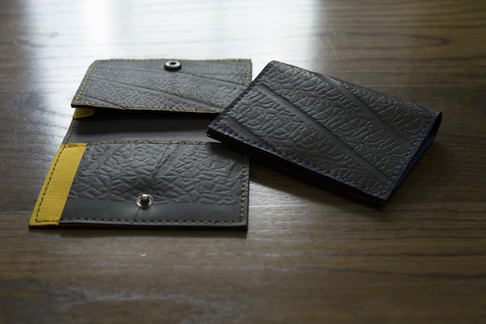 Paguro Upcycle vegan slim card holder wallets with textured black material and snap closures on wooden surface
