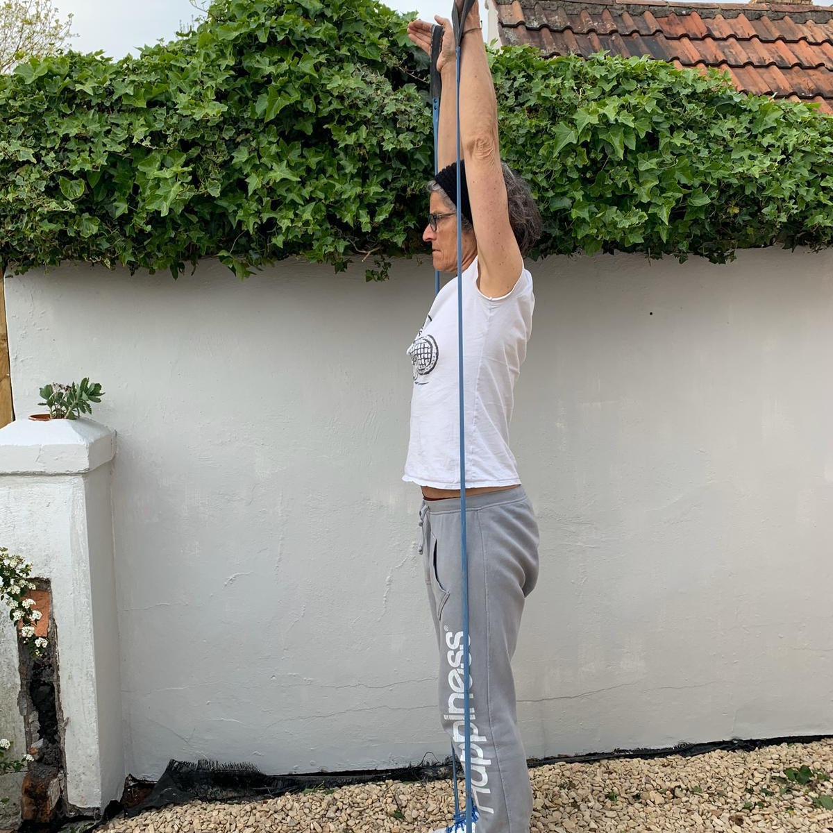 Woman exercising outdoors using a blue upcycled resistance band from Paguro Upcycle for stretching