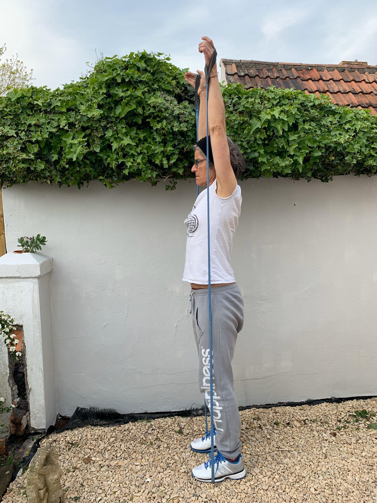 Woman exercising outdoors using a blue upcycled resistance band from Paguro Upcycle for stretching