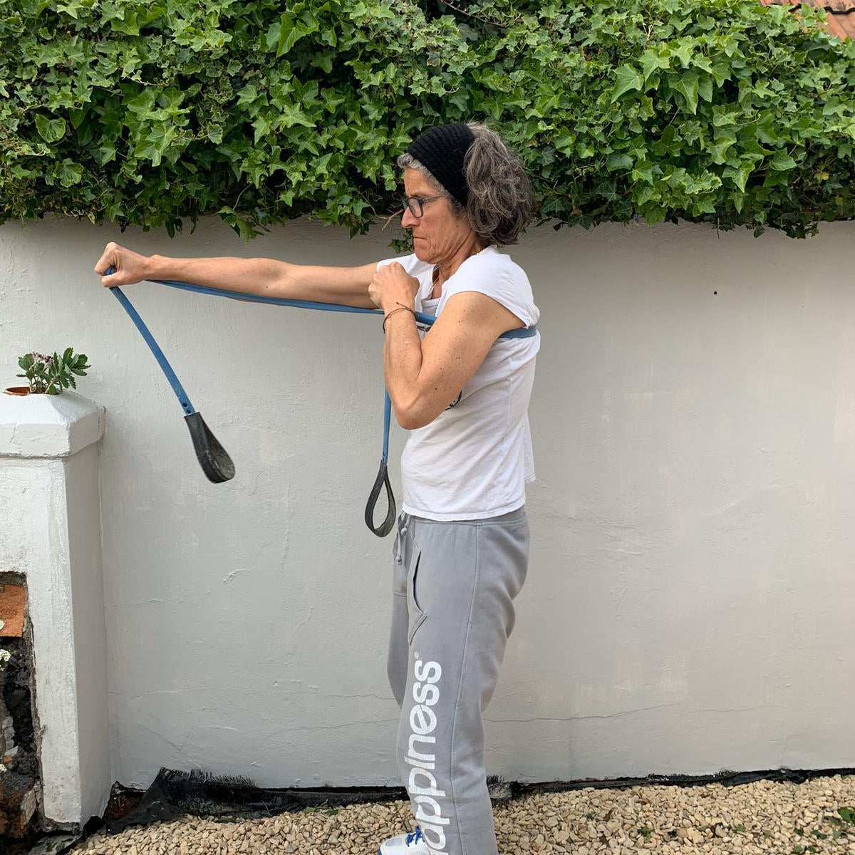Woman exercising outdoors using a Paguro Upcycle upcycled resistance band in blue for strength training