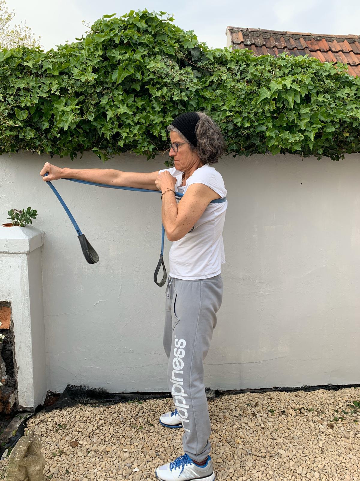 Woman exercising outdoors using a Paguro Upcycle upcycled resistance band in blue for strength training